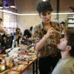 A team of makeup artists working on models in a bustling studio environment.