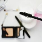 Flat lay of cosmetics featuring a mascara brush, perfect for beauty and fashion themes.
