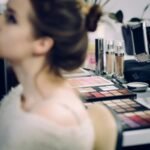 A woman receiving professional makeup in a studio with various cosmetics in focus.